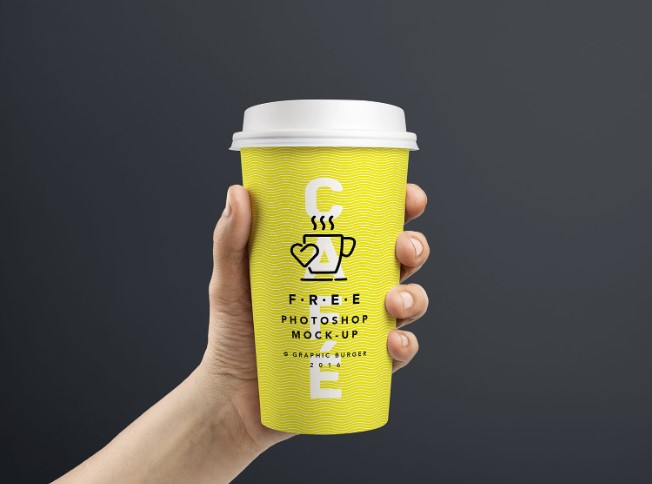 Free mockup of paper coffee cup in hand, mockup PSD